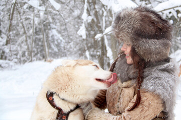 Winter landscape. Snowy forest. Cheerful young woman. Communication with a husky dog. Happiness of mutual understanding. Christmas.