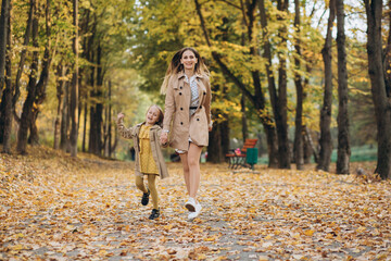 Fototapeta premium Happy mother and her beautiful daughter have fun and walk in the autumn park.