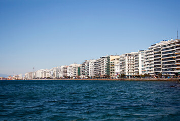 Waterfront buildings facades along Thessaloniki embankment busy with shops and cafes under clear spring sky
