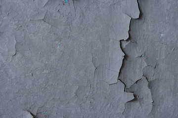 Peeling paint on the wall. Old concrete wall with cracked flaking paint. Weathered rough painted surface with patterns of cracks and peeling. High resolution texture for background and design. Closeup