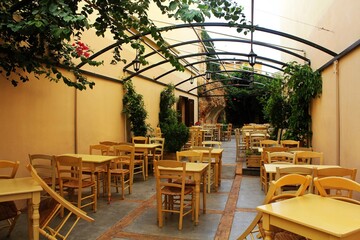 Chania, Crete / Greece - August 8th 2015: Empty greek mediterranean restaurant with yellow furniture and lot of green inside in Chania, Crete Island, Greece