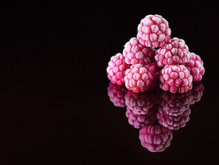 Handful of frozen raspberries covered with frost mirrored or reflected on glass as a menu design or pattern element on black background with a horizontal or vertical frame for text aka copy-space