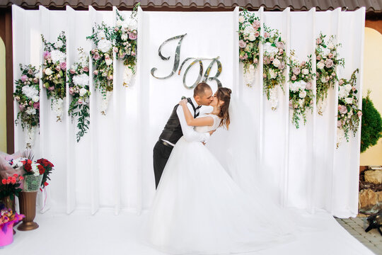 Newlyweds kiss on the background of their photo area with Initials