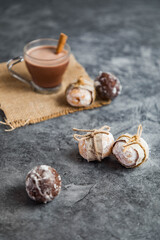 Obraz na płótnie Canvas Hot chocolate with cinnamon on sackcloth. Mini doughnuts in the shape of a ball, filled and wrapped in recycled paper. Dark grey marble background. Christmas background. Breakfast.