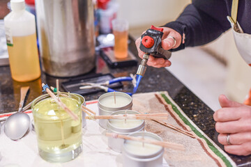 Creative occupation of candle making showing the pouring of liquid wax into jars