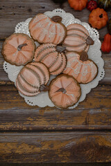 Pumpkin shaped cookies with royal icing on white plate and wooden table, copy space