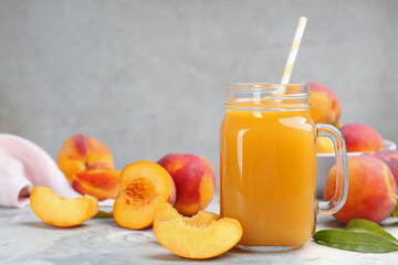 Natural peach juice and fresh fruits on grey table