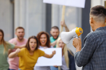 Protest leader with megaphone talking to crowd outdoors