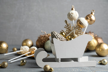Delicious Christmas themed cake pops and festive decor on wooden table against grey background