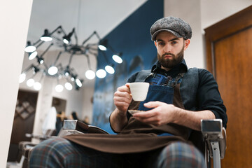 Barbershop worker drinks coffee during a break