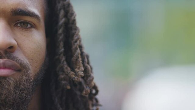 Half face portrait of attractive black male with long hair looking to camera with a serious expression