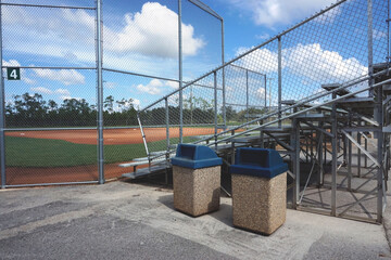 Trash and Recycle Bins in Front of a Baseball Field 