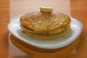 delicious breakfast hot cake with butter and honey on a white plate
