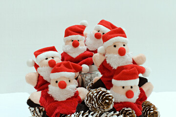 group portrait of funny santa claus toys among fir cones on blurred white background