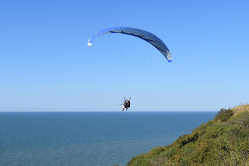 Two man flying on paraglide over the sea shore