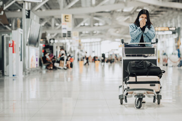 Asian woman traveler wearing mask protect from coronavirus with luggage trolley sneezing