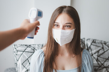 Measurement temperature of young woman with mask by infrared thermometer to check people with fever...