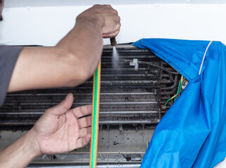 Male technician cleaning air conditioner.