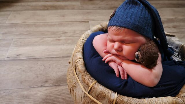 Adorable, cute and touching 10-days-old newborn baby boy sleeping in wicker basket in photo zone, grimacing, yawning and making faces. Childhood, infancy, parenthood, motherhood. 4 k video