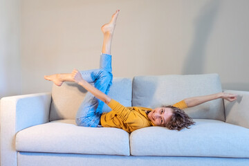 Fun and joy. Festive mood. Happy woman lies on the sofa with raised legs, female rest and relaxation. Photo of a crazy cheerful positive joyful contented woman in a good mood, screaming, shouting that