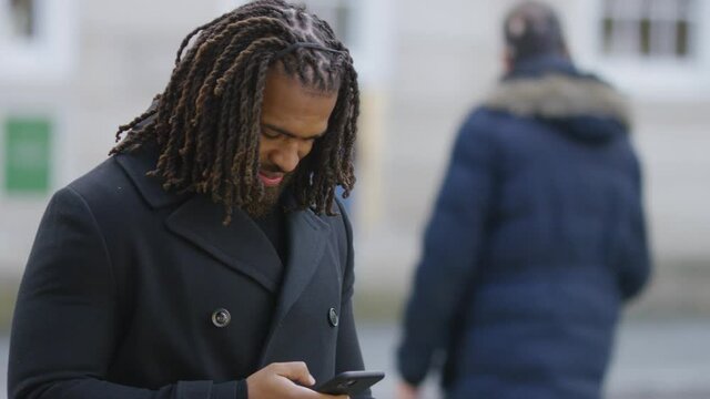 Attractive man in the city using his cell phone as he stands waiting