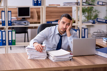 Fototapeta premium Young male employee unhappy with excessive work