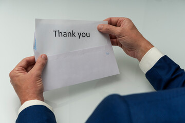 HANDS OF AN EXECUTIVE OPENING A LETTER OF GRATITUDE WITH THE TEXT OF THANK YOU. BUSINESS CONCEPT.