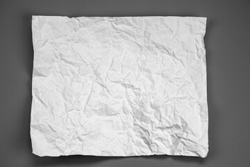 white and gray crumpled paper on  gray background. crush paper so that it becomes creased and wrinkled.