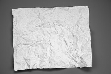 white and gray crumpled paper on  gray background. crush paper so that it becomes creased and wrinkled.