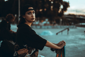 Chica joven urbana con mascarilla coronavirus pandemiua covid-19 en skatepark con patin skate...