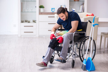 Fototapeta na wymiar Young leg injured contractor in wheel-chair cleaning the house