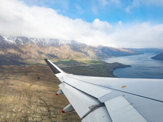 Looking at the hills around Queenstown, New Zealand over the wing of a plane. - Powered by Adobe
