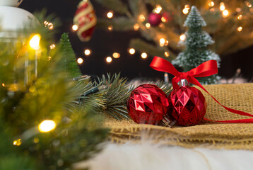 Red christmas ball with bow ribbon and branches on the table.