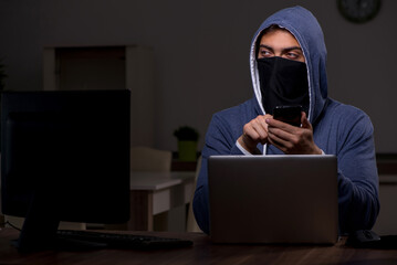 Male hacker hacking security firewall late in office