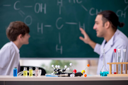 Young chemistry teacher and schoolboy in the classroom