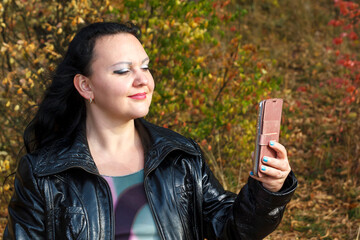 pregnant woman on a park bench in autumn makes a selfie.