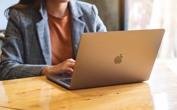 Oct 16th 2020 : A woman using and working on Apple MacBook Pro laptop computer on wooden table , Chiang mai Thailand