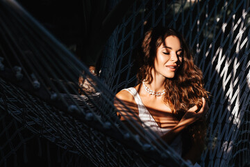 Attractive young woman is relaxing outdoor while lying in hammock. Beauty treatment concept.