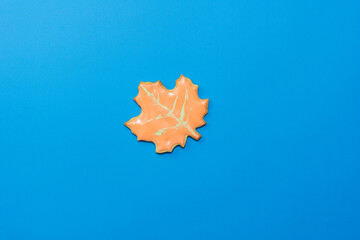 Sweet homemade leaf cookie with icing isolated on dark blue background minimal flat lay composition.