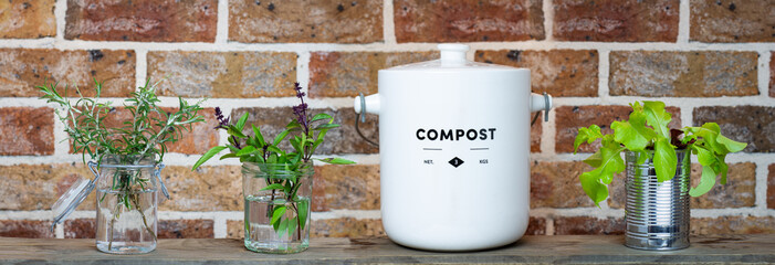Kitchen waste compost pot and reused jars and tin on kitchen shelf. Recycle and reuse for zero...
