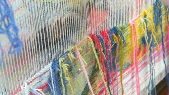 Handmade carpet embroidery. Women's hands create a pattern using multi-colored threads. Hammer for embroidery quors, stuffing threads. Close up view.
