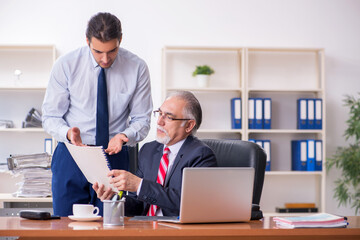 Fototapeta premium Old boss and young male employee in the office
