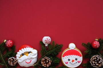 Christmas and New Years  holiday. santa claus and snowman christmas gingerbread cookies with fir branches and cones, christmas balls on a bright burgundy background.Sweets for the winter holidays. 