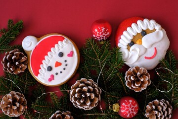 Christmas and New Years  holiday. santa claus and snowman christmas gingerbread cookies with fir branches and cones, christmas balls on a burgundy background.Sweets for the winter holidays. 