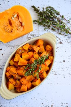 Roasted cubed butternut squash with thyme on white background