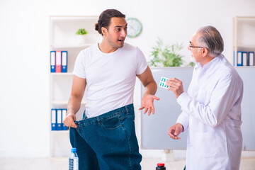 Fototapeta premium Doctor dietician and happy patient wearing large trousers