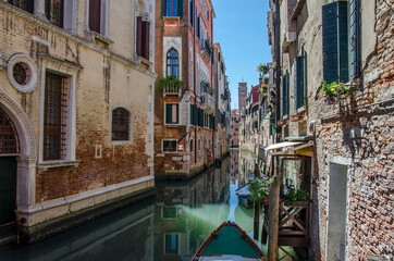 Fototapeta na wymiar Narrow canal with old colorful houses in Venice, Italy. Traditional gondola in Venetian water canal. Narrow canal street with colorful buildings and boats in Venice.