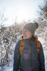 Fototapeta na wymiar Smiling woman with a backpack on a background of a snowy forest