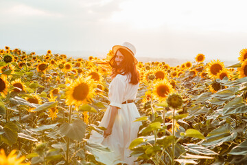young beautiful woman at sunflowers field on sunset