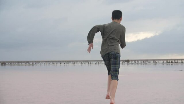 Snappy boy running fast along a sandy sea shore in summer in slow motion  